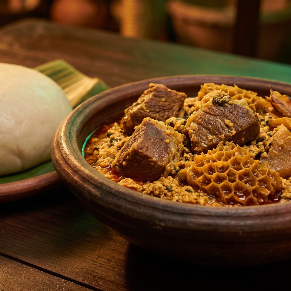 A bowl of Nigerian Egusi soup with beef and tripe, served with pounded yam on a banana leaf.